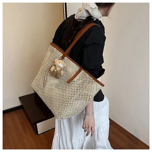 Détail du sac cabas tissé crème avec anses en cuir marron et pendentif ours mignon