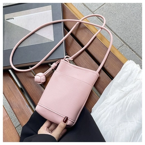 Close-up of pink litchi grain leather phone bag with knot decorative shoulder strap