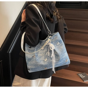 Detail of blue denim tote bag with silver butterflies and pearl lace accessories