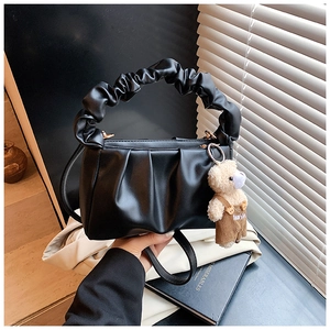 Detail of black pleated shoulder bag with scrunchie handle and cute teddy bear charm