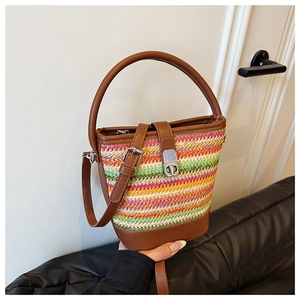 Detail of colorful rainbow woven straw bucket bag with leather handles and metal twist lock