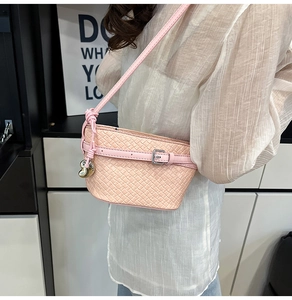 Dettaglio borsa a spalla rosa in pelle intrecciata con fibbia e ciondolo a cuore