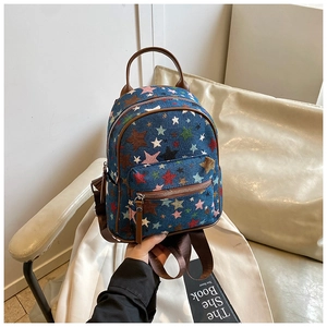 Detailed view of blue denim mini backpack with colorful star embroidery and brown leather trim
