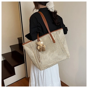 Détail macro du sac cabas en paille tissée beige avec poignée PU et breloque ours en peluche
