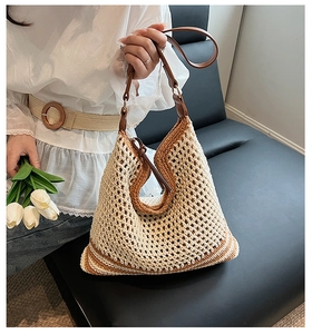 Detail of woven straw tote bag featuring contrast leather handles and bohemian knit pattern