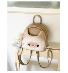 Close-up of cute cat-shaped mini backpack featuring 3D ears and a plush bear charm