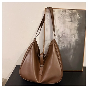 Detail view of large dark brown tote bag with metal buckle and premium leather texture