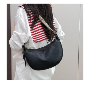 Detail of black pebbled leather crescent bag with jacquard strap worn by a model