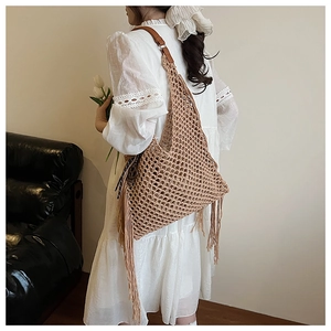 Détail d'un sac cabas en tricot ajouré avec de longues franges et bandoulière en cuir