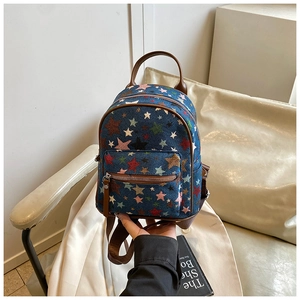 Detail of mini denim backpack featuring colorful star patterns and brown leather handle