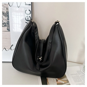 Close-up of black leather tote bag featuring a large gold square buckle and wide strap
