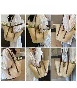 Detail view of woven straw tote bag featuring brown leather straps and decorative tassels