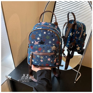 Detail of star-pattern denim backpack with brown leather trim and metallic zipper
