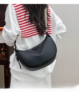 Detail of black pebbled leather dumpling bag with wide beige woven shoulder strap for women