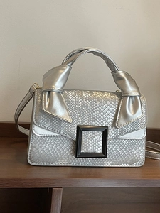 Silver snakeskin embossed small square bag with large black buckle and bow handle