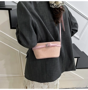 Dettaglio borsa a tracolla intrecciata rosa con fibbia in pelle indossata da modella