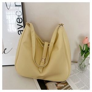 Detail view of large pale yellow hobo tote bag with smooth finish and gold buckle