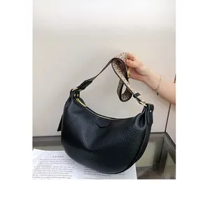 Detail of black lychee grain leather dumpling bag with geometric jacquard strap