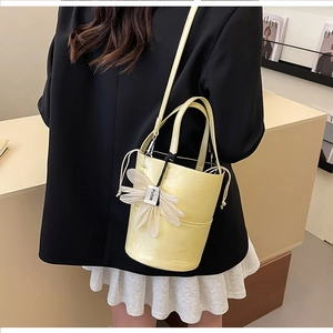 Detail view of yellow bucket bag with a 3D white flower charm and drawstring inner pouch