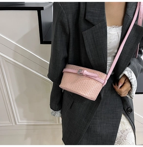 Dettaglio della mini borsa a tracolla rosa stampa cocco abbinata a un blazer grigio
