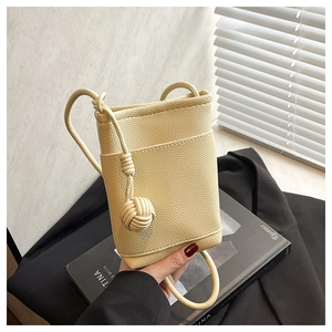 Detail of beige litchi grain leather mini bucket bag with unique knot ball accessory