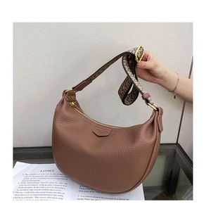 Detail of brown litchi pattern leather dumpling bag with retro wavy woven strap