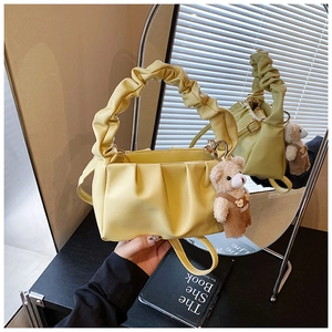 Detail view of yellow pleated cloud shoulder bag with cute bear charm and long strap