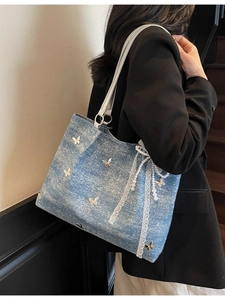 Blue denim tote bag with silver butterflies and lace trim shown on a model