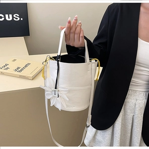Detail view of white PU leather bucket bag with floral charm on a chic blazer outfit