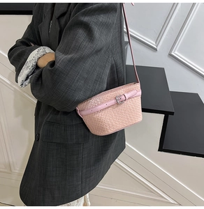 Dettaglio della borsa a tracolla rosa intrecciata con fibbia argento indossata dal modello