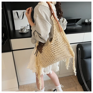 Détail d'un sac au crochet beige avec franges et bandoulière en cuir marron foncé