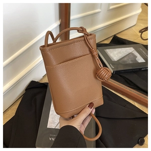 Detail of brown litchi pattern leather mini bucket bag with knotted shoulder strap