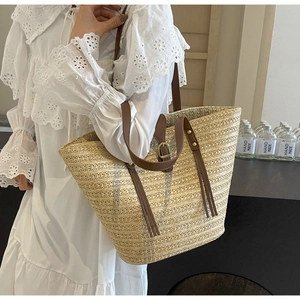 Side view of woven straw tote bag with brown leather straps on white lace dress