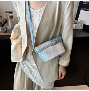 Dettaglio borsa a tracolla azzurra con trama intrecciata su un abito beige