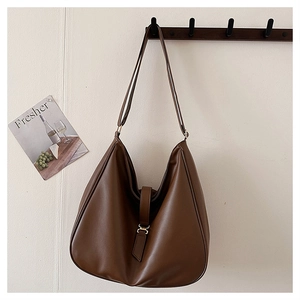 Detailed view of brown faux leather hobo tote with gold buckle and slim shoulder strap