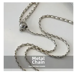 Detail of silver metal chain with white leather weave and adjustable diamond pattern ball