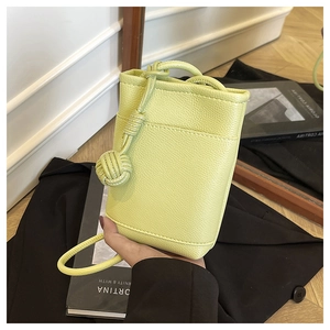 Close-up of lime green mini crossbody bag featuring textured leather and knot detail