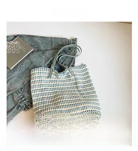 Detail view of woven blue and white striped tote bag with long leather shoulder strap