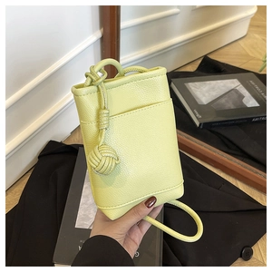 Detail showing the light green pebble leather texture and hand-knotted decor on bucket bag