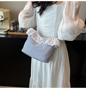 Detail of blue striped canvas crossbody bag with white lace trim in a cafe setting