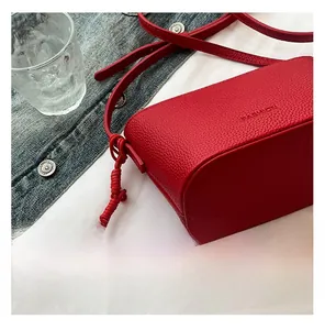 Detail der roten Beuteltasche aus Leder mit Kieselprägung und silbernem Herzanhänger