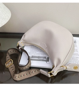 Detailed view of cream pebble leather crescent bag with ethnic style jacquard strap