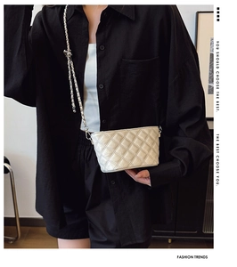 Miniature cream quilted bag with silver chain strap shown on model for size perspective