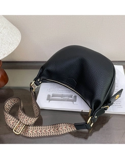 Close-up of black lychee grain leather dumpling bag with woven strap and gold hardware