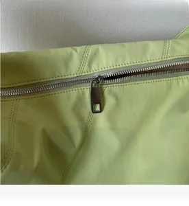 Nahaufnahme des silbernen Metallreißverschlusses an einer hellgrünen Nylon-Tasche