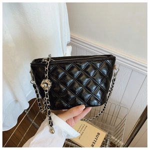 Detail of black quilted leather bucket bag with silver chain strap and metal ball