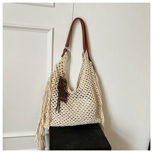 Détail d'un sac cabas en maille crème avec de longues franges et une poignée en cuir