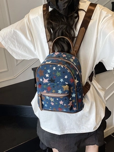 Back view of stylish blue canvas backpack with colorful star print and brown leather straps