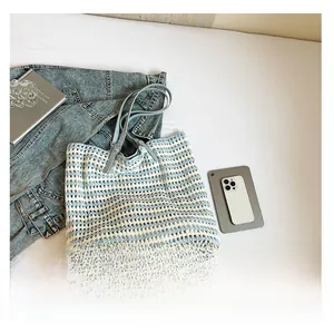 Detail of blue and white striped crochet tote bag with leather strap and woven texture