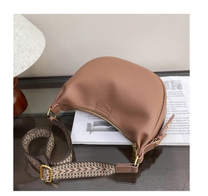 Detail of lychee pattern leather hobo bag with a wide woven geometric strap